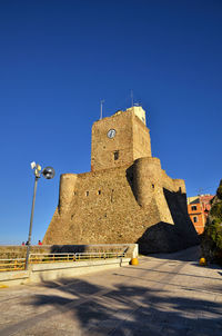 Low angle view of fort against clear blue sky