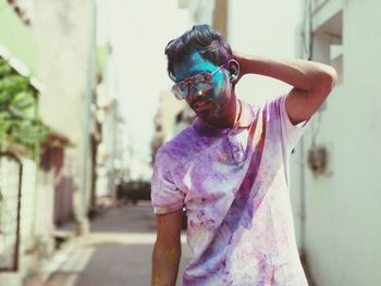 Man wearing sunglasses while covered with powder paint in city