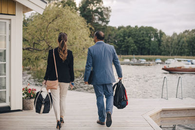 Rear view of mature couple walking at holiday villa by lake