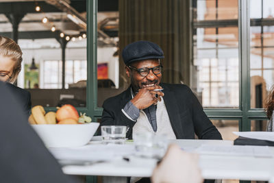 Happy businessman with hand on chin laughing during meeting at office