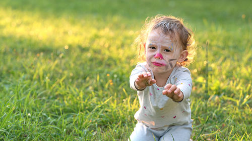 Portrait of cute girl playing with teddy bear on field