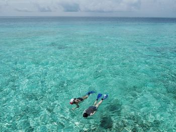 High angle view of people snorkeling in turquoise sea against sky