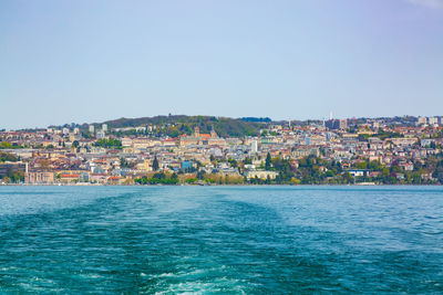 Aerial view of townscape by sea against clear sky