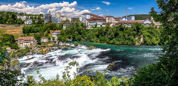 Scenic view of river by buildings against sky