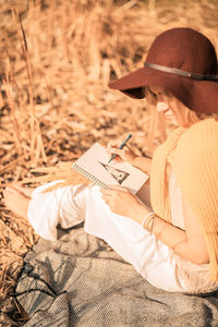 Woman reading book while sitting on field