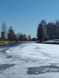 Snow covered landscape against clear blue sky