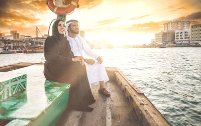 Smiling couple sitting in boat on river