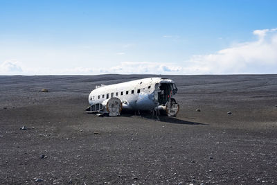 Abandoned damaged plane wreck at black sand beach in solheimasandur against sky