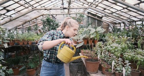 Caucusian woman holding a water can in greenhouse