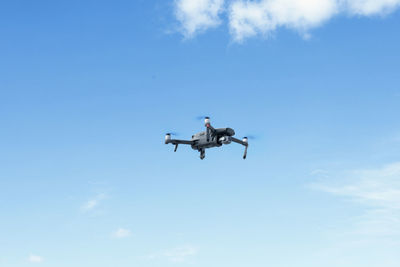 Low angle view of drone flying against blue sky