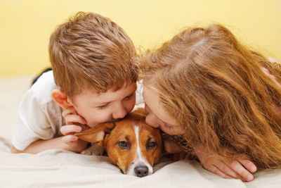 Little boy and girl kissing a puppy jack russell dog.