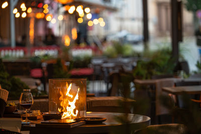 Blurred photo of street cafe terrace decorated with flame heate, evening street lights, fcozy mood