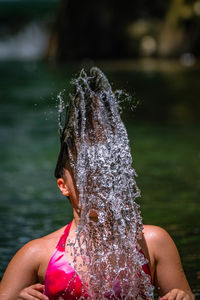 Teenage girl tossing hair in lake