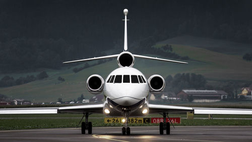 Airplane at airport runway against sky