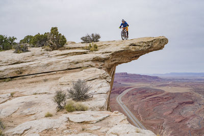 Man climbing on rock formation against sky