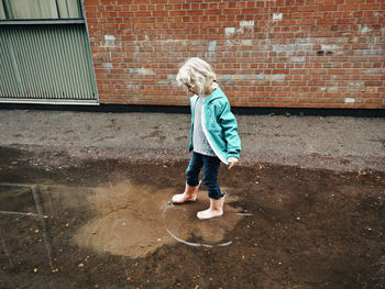 Full length of girl standing against brick wall