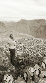 Rear view of man on rock against sky