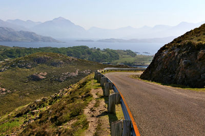 Scenic view of road by mountains against sky