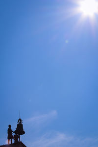 Low angle view of silhouette men against blue sky