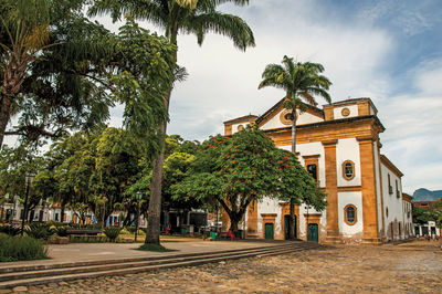 Overview of old colored church, garden with trees and cobblestone street in paraty, brazil