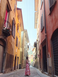 Rear view of woman walking on street amidst buildings