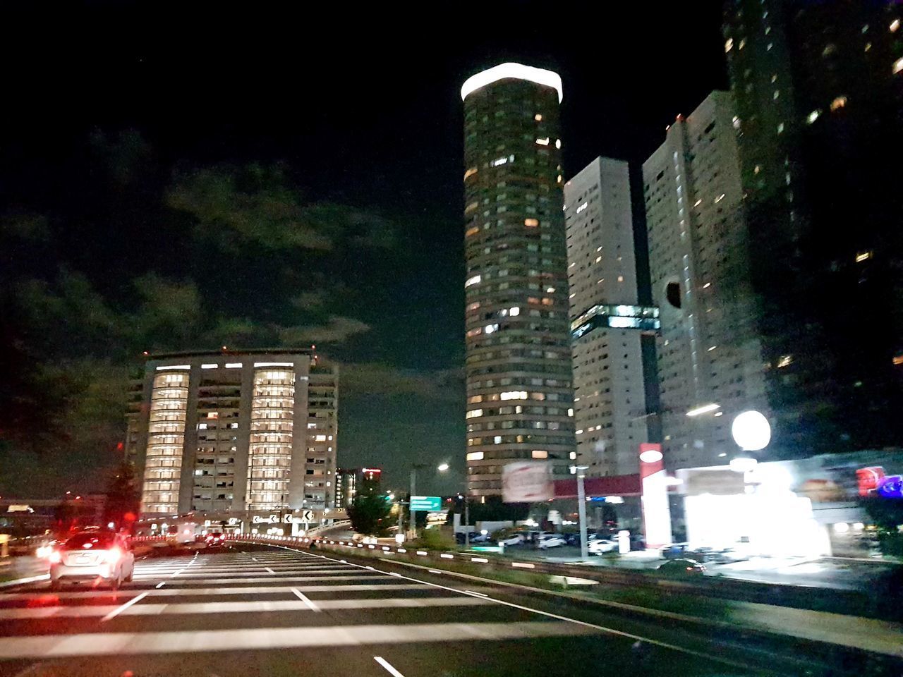 ILLUMINATED STREET AMIDST BUILDINGS AT NIGHT