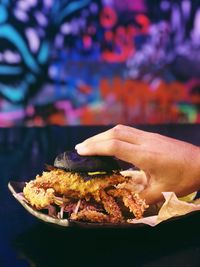 Close-up of hand holding burger in plate