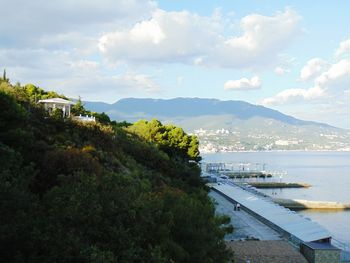 High angle view of city by sea against cloudy sky