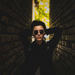 Portrait of woman in sunglasses standing amidst wall