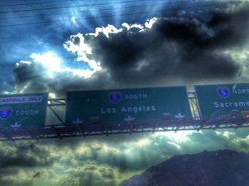 Road sign against cloudy sky