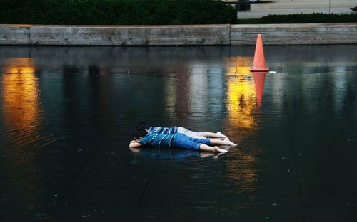 Playful siblings lying down on wet road in city