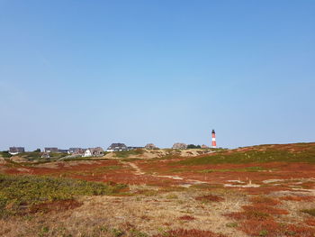 Lighthouse on field against clear sky