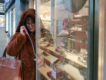 Young woman looking through window in city