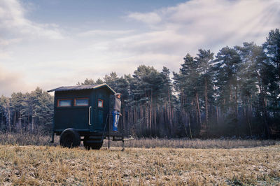 Full length of man standing by shack against trees