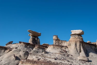 Low angle view of rock formation against clear blue sky