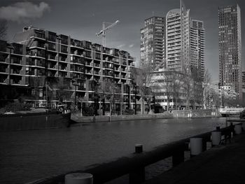 Buildings by river against sky in city