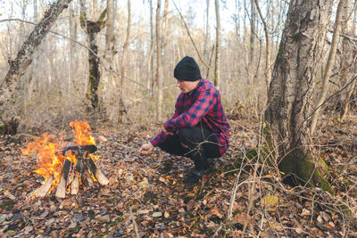 Full length of man sitting in forest during winter