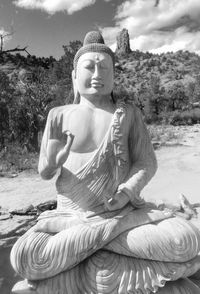 Statue of buddha sitting against plants