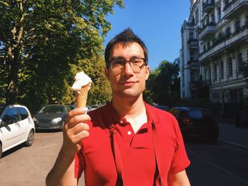 Portrait of young man holding ice cream cone on street