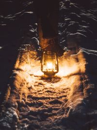 Low section of man standing on illuminated street at night