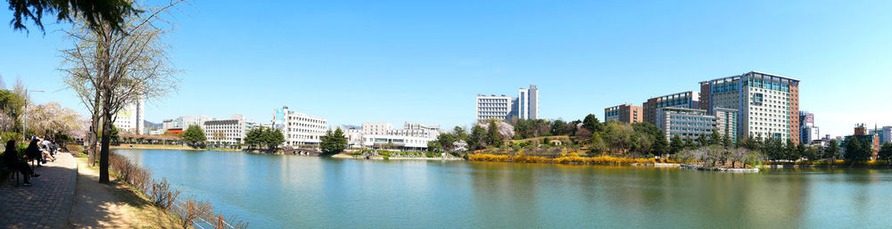 Panoramic view of river and buildings against clear blue sky