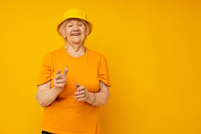 Portrait of young woman gesturing against yellow background