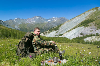 Full length of man sitting on land against mountains