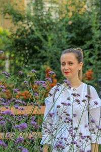 Young woman standing by plants on field