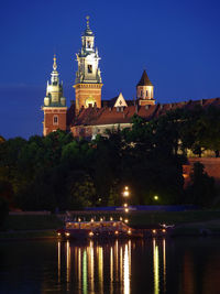 Wawel castle illuminated by night with reflections in vistula river