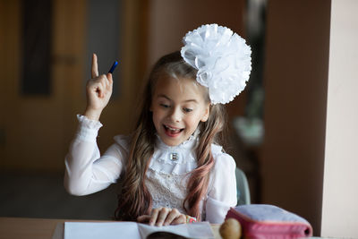 Cute girl studying while sitting by table at home