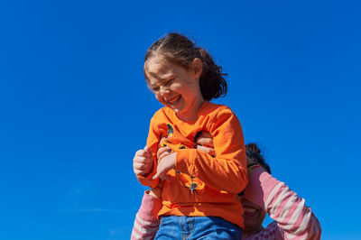 Pretty girl being held up in the air by mom against a blue sky