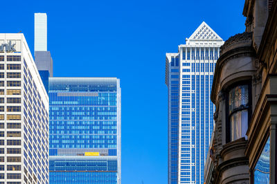 Low angle view of modern buildings against clear blue sky