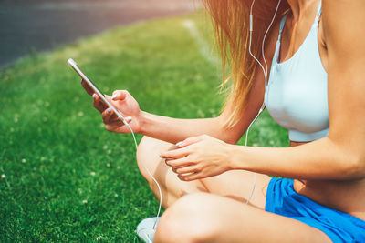 Midsection of woman using mobile phone in grass