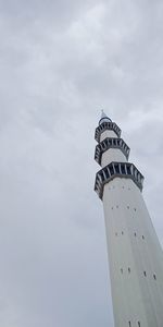 Low angle view of lighthouse by building against sky